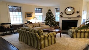 A cozy living room with a striped sofa set, a Christmas tree, and a fireplace. - Miner Cottage-Historic Antique Home just steps from the Equinox Resort (Manchester)