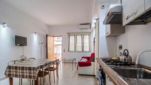 A modern kitchen with a dining area, a red chair, and a TV mounted on the wall.