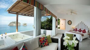 A modern room with a large bathtub, a bed with colorful pillows, and a view of the sea. - Great RATES with full STAFF!  Relax and enjoy! (PUERTO VALLARTA)