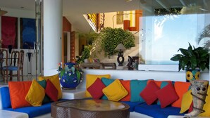 A modern living area with a colorful sofa set, a round coffee table, and a view of the ocean. - Great RATES with full STAFF!  Relax and enjoy! (PUERTO VALLARTA)