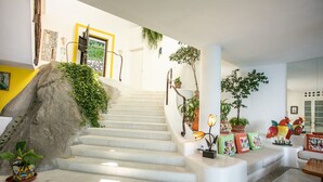 A staircase with a stone wall on one side and a white wall on the other, leading to a landing with a sofa and decorative pillows. - Great RATES with full STAFF!  Relax and enjoy! (PUERTO VALLARTA)