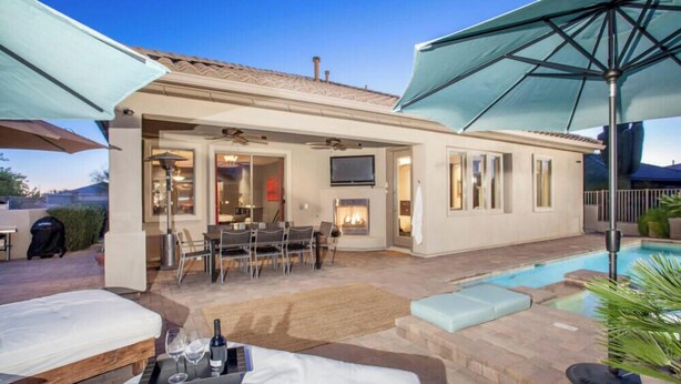 Un'area living esterna moderna con piscina, mobili da patio e ombrelloni.