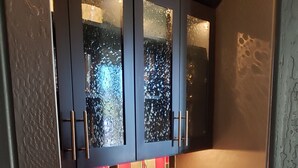Una cucina moderna con mobili scuri, un piano di lavoro rosso e un forno a microonde integrato.