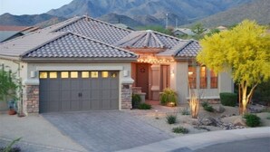 Una casa residenziale con garage, portico anteriore e montagne sullo sfondo.