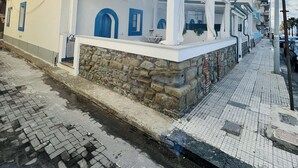 A building with a white facade, blue doors, and a stone base. - Old fisherman's house overlooking the sea, along the Capo d'Orlando promenade (Capo D'orlando)