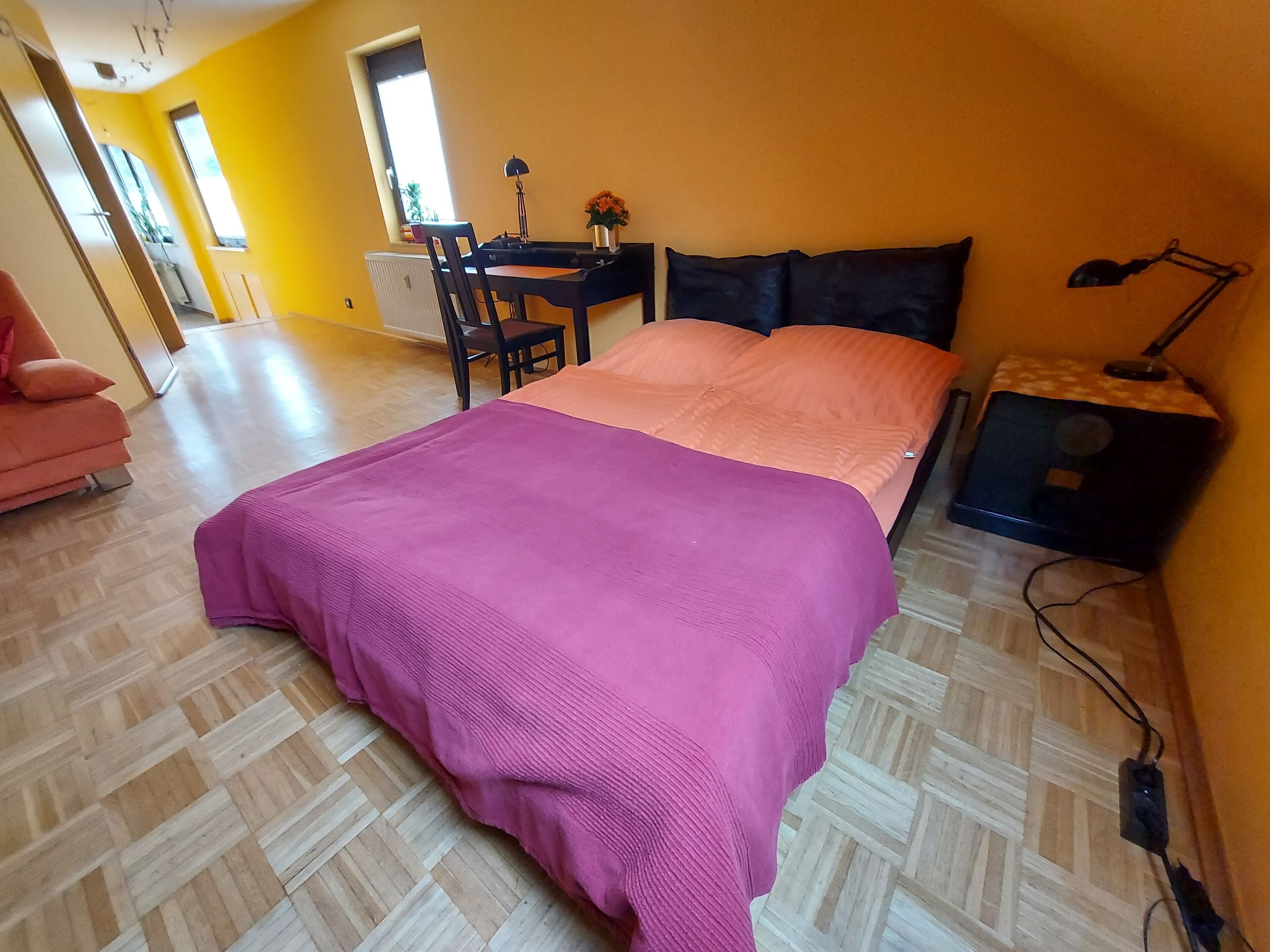 Une chambre à coucher avec un lit, un bureau, une chaise et une table de chevet.