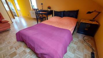 Une chambre à coucher avec un lit, un bureau, une chaise et une table de chevet.