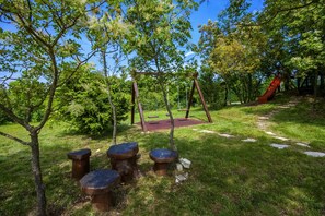 A park with a playground, including swings, a slide, and stone seating.