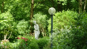 A garden with a statue, a lamppost, and various plants. - Stylish bright apartment, very conveniently. Metro just around the corner. Internet (München)