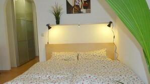 A bedroom with a bed, a nightstand, a potted plant, and a painting on the wall. - Stylish bright apartment, very conveniently. Metro just around the corner. Internet (München)