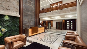 Um lobby moderno com sofás de couro, balcão de recepção e piso com padrão geométrico.