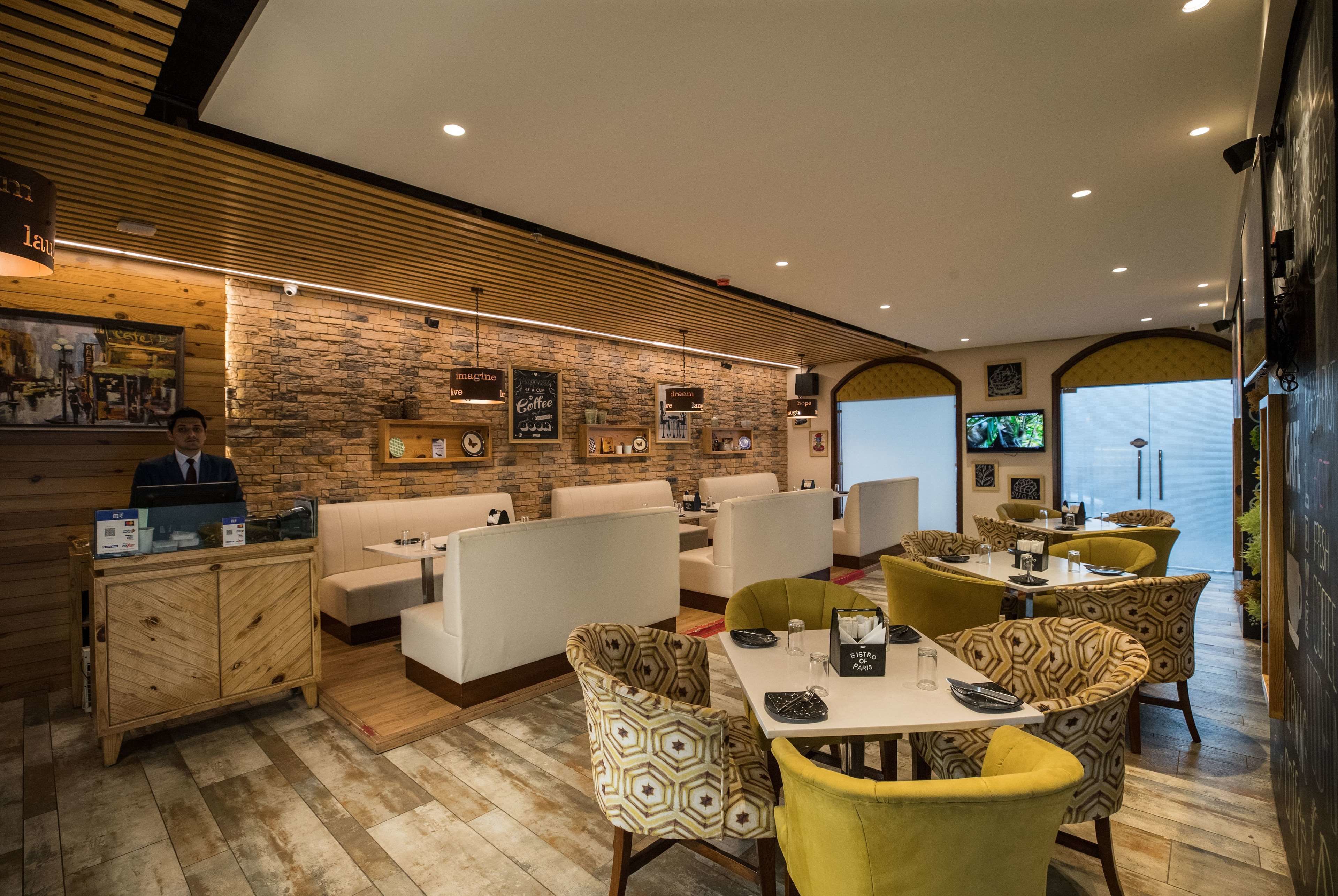 Een modern restaurant met houten lambrisering, stenen muren en verschillende zitplaatsen, waaronder booths en stoelen met een patroon.