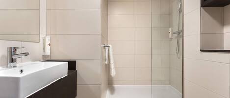 Une salle de bain moderne avec un lavabo blanc, une douche en verre et des toilettes blanches.