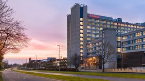 Moderni hotelli, jossa on selkeästi näkyvä «Ramada»-kyltti. Rakennuksessa on useita kerroksia, paljon ikkunoita ja hyvin valaistu julkisivu.