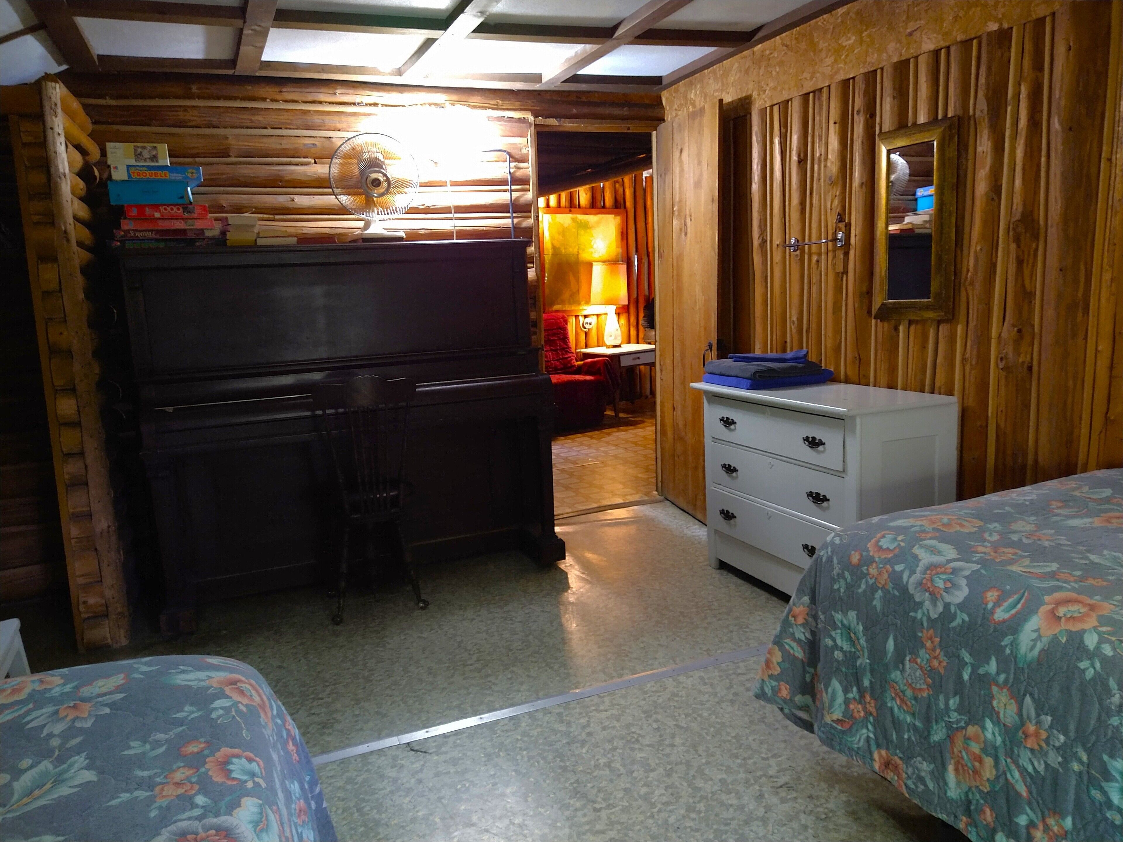 A room with a wooden desk, a chair, a bed with floral bedding, a dresser, and a mirror on the wall.