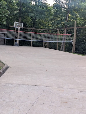 A basketball court with a net, wooden posts, and a basketball hoop.