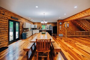 A spacious kitchen with wooden walls and a large dining table. - Secluded, Private 5000 Square Foot Luxury Lodge Located On 20 Wooded Acres. (Cambridge)