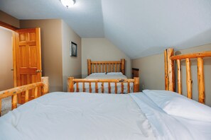 A bedroom with a wooden bed frame, a door, and a wall-mounted picture. - Secluded, Private 5000 Square Foot Luxury Lodge Located On 20 Wooded Acres. (Cambridge)