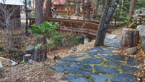 A stone pathway leading through a wooded area with a wooden bridge.