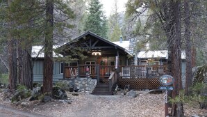 A lodge with a stone facade, wooden deck, and a sign indicating it is The Redwoods in Yosemite.