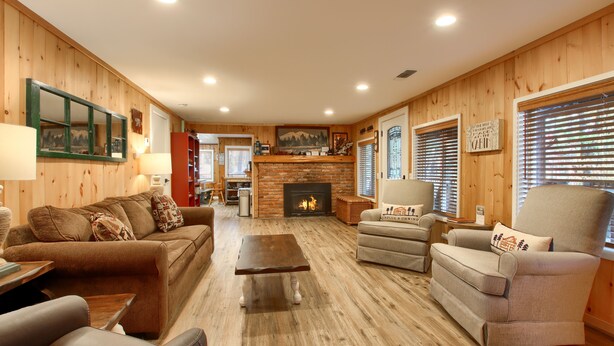 A cozy living room with wooden walls, a fireplace, and comfortable seating.