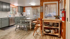 A kitchen with wooden cabinets, a sink, a dining table, and a chair.