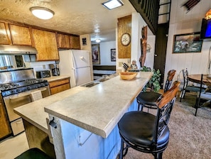 A kitchen with wooden cabinets, a granite countertop, a stove, and a refrigerator.