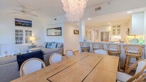 Una sala de estar moderna con una mesa de comedor, sillas de mimbre, un sofá y un ventilador de techo.