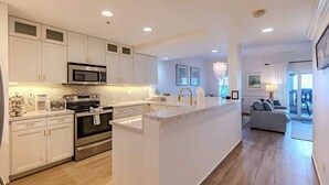 Una cocina moderna con armarios blancos, electrodomésticos de acero inoxidable y una isla central.