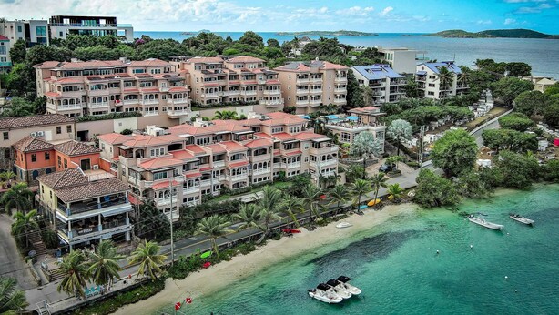 Un hotel frente al mar con varios balcones y barcos en el agua.