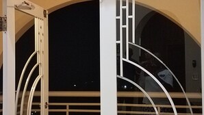 A room with a large window, a door, and a metal railing.