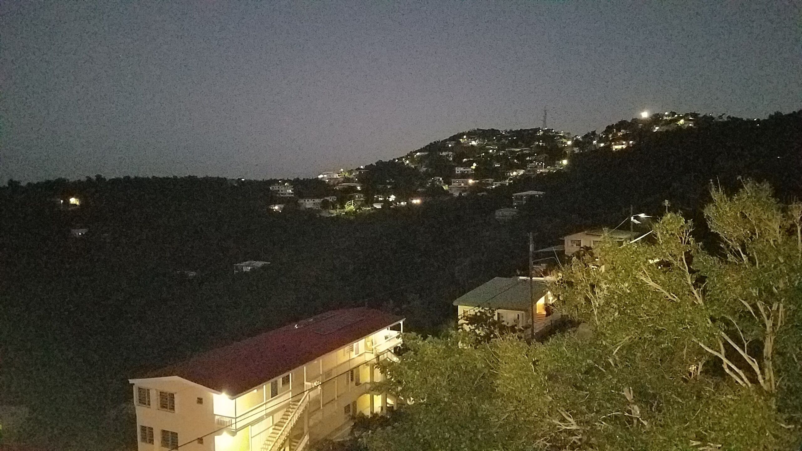 A hillside residential area with houses and a building with a red roof.