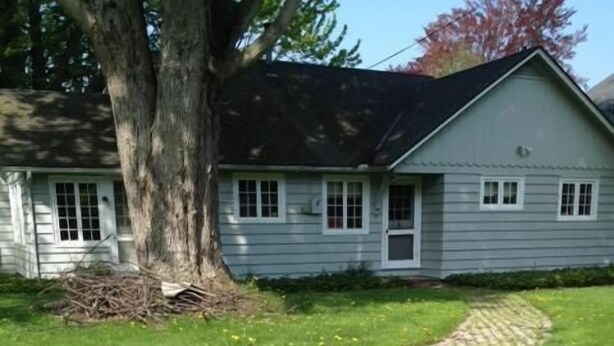 A paved pathway leading to a house with a large tree and a grassy lawn. - Bay Beach house. No roads to cross to beach.  Private beach.  (Fort Erie)