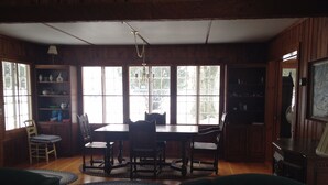 A dining room with a wooden table and chairs, a chandelier, and large windows. - Bay Beach house. No roads to cross to beach.  Private beach.  (Fort Erie)