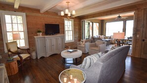 A spacious living room with wooden floors, a large sofa, a coffee table, and a television on a cabinet.