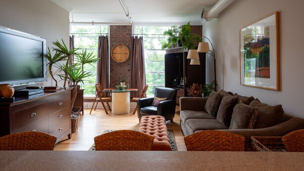 A living room with a television, sofa, armchairs, a coffee table, and a dining area with a table and chairs. - Very Special Downtown Asheville Loft  (Asheville)