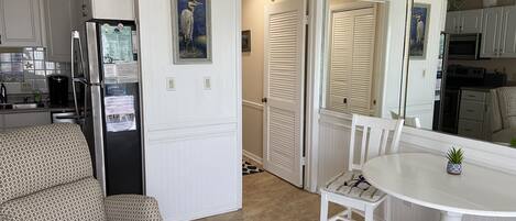 A compact kitchen with a refrigerator, microwave, and stove. There is a dining area with a table and chairs.