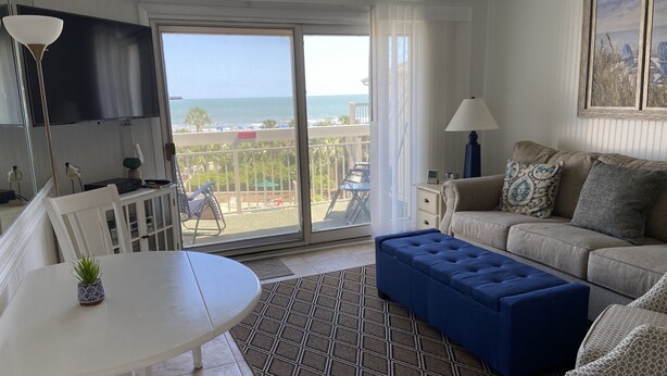 Une chambre avec un balcon, un canapé, une table et un téléviseur.