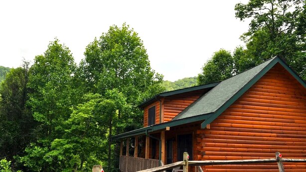 A wooden cabin with a porch, surrounded by dense forest and hills. - Deer Country Vacation Cabins #3 - Long Range View, Dogs Friendly (Waynesville)