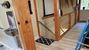A wooden staircase with a metal handrail, a patterned rug, and a view of the outdoors through a window.