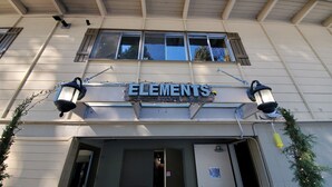 A building with a sign reading "ELEMENTS" and a sign below stating "WIND, WATER, EARTH, FIRE".