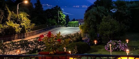 Un balcon avec une table, une lanterne et une vue sur un lac et des montagnes au crépuscule.