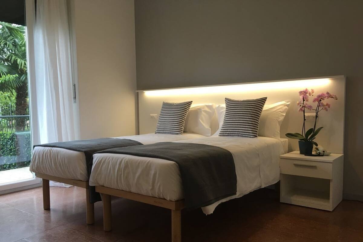 A modern bedroom with a bed, bedside tables, and a potted plant.
