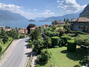 A residential area with a road, houses, and a lake with mountains in the background. - Hotel Loveno (Menaggio)
