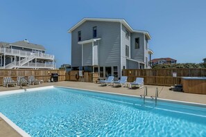 A swimming pool with lounge chairs, a wooden deck, and a two-story building with a balcony. - Judge's Chambers | 415 ft from the beach | Private Pool, Hot Tub | Corolla (Corolla)