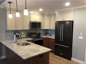 Enjoy cooking in this well-equipped kitchen with a sink, stainless steel refrigerator, and oven.