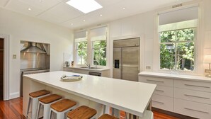 Una cucina moderna con isola centrale, elettrodomestici in acciaio inossidabile e ampie finestre che offrono vista sul verde.