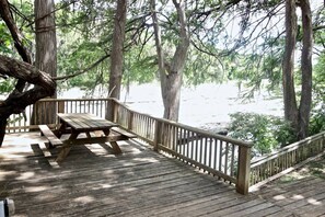 Eine Holzterrasse mit Picknicktisch und Geländer mit Blick auf einen Strand.