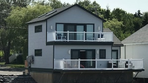 A two-story building with a balcony on the upper floor. - Elegant oceanfront home on Southwest Harbor minutes to trails and village center (Southwest Harbor)