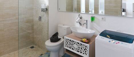 Une salle de bain avec une douche à parois de verre, des toilettes, un lavabo avec un miroir au-dessus et des carreaux de sol à motifs.